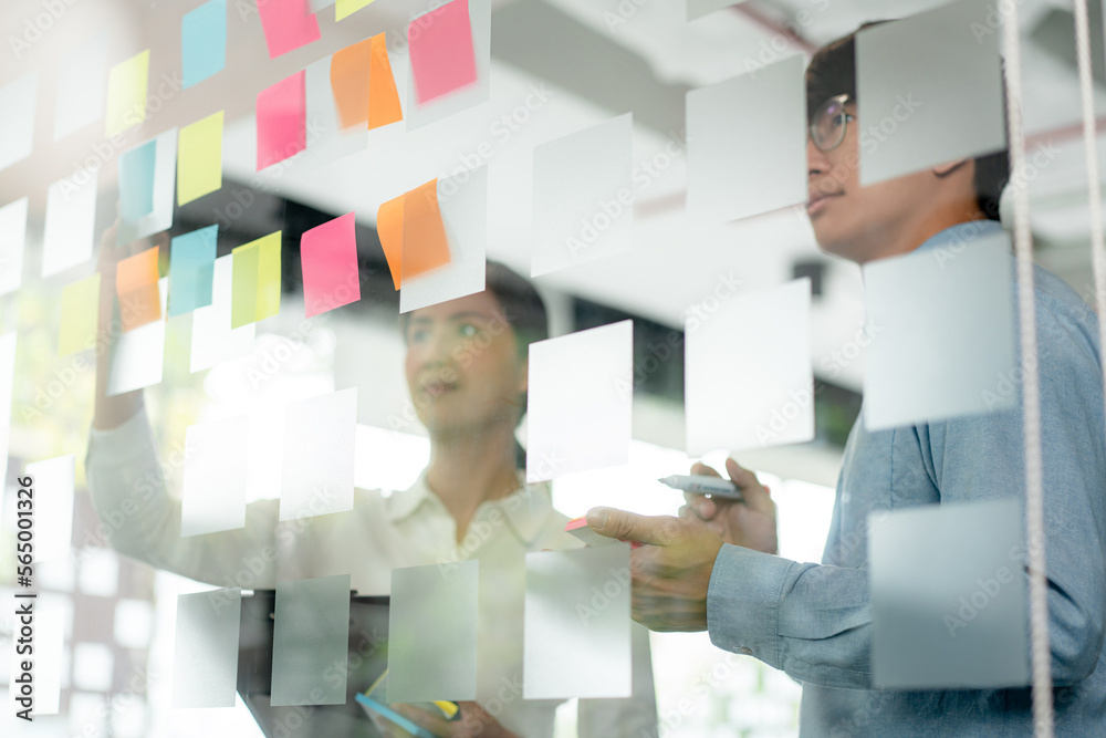 Poster two business executive team holding and taking notes keyword on board wall to brainstorm about a new