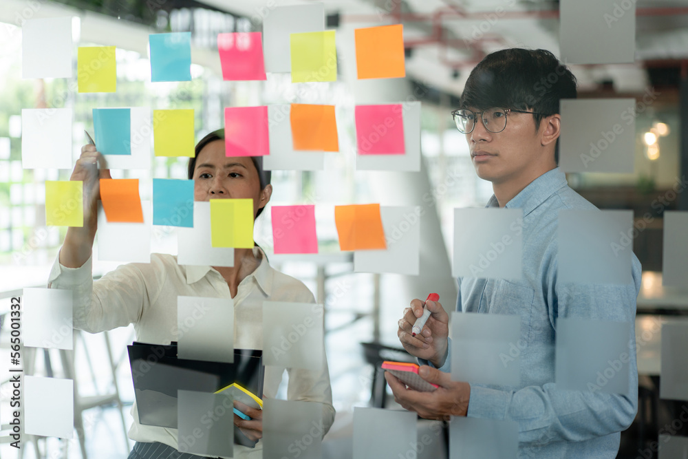 Aufkleber two business executive team holding and taking notes keyword on board wall to brainstorm about a new