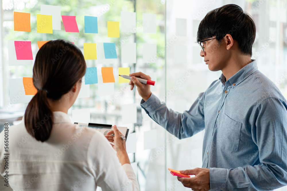 Poster two business executive team holding and taking notes keyword on board wall to brainstorm about a new