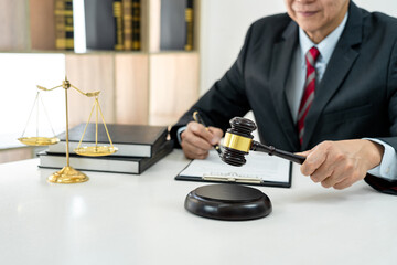 Fototapeta na wymiar A male lawyer or notary working with contract papers, book and wooden gavel on table in courtroom, Law and Legal services concept