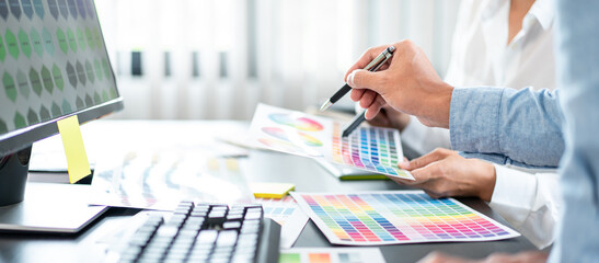 Team of creative graphic designer working on color swatch samples chart for selection coloring in inspiration to create new collection at workplace