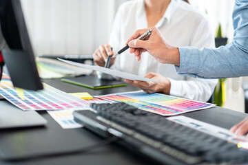 Two creative graphic designer team working on color selection and drawing on graphic tablet, Color swatch samples chart for selection coloring in inspiration to creativity at workplace