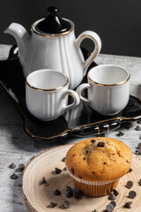 Muffin or cupcake with chocolate chips on wooden table background. Concept of making industrial or homemade pastries.