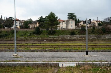 Fototapeta na wymiar Ales, Occitanie, France, Deserted platform, railways and residential houses in the background