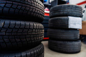 Selective focus on new tires in a mechanic's shop with old ones in blurry background.