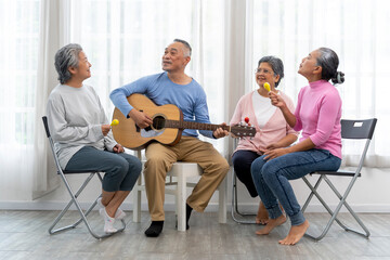 Group of senior peoples enjoy playing guitar and singing together in living room - 565003724