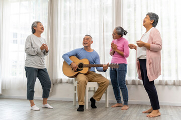 Group of senior peoples enjoy playing guitar and singing together in living room