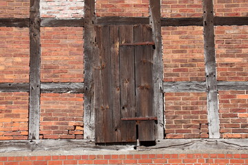 Alte Holztür an einer roten Hauswand aus Backstein mit Fachwerkbalken, Deutschland