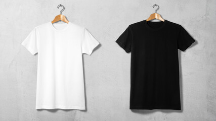 コンクリートの壁にハンガーで吊るされた、白と黒のＴシャツ