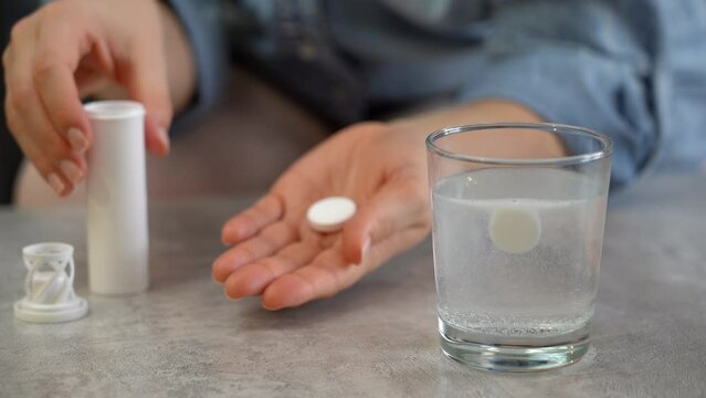 Female hands open jar of medicine on background of effervescent pill dissolving in glass of water. Take pills, drugs, medicament. Health care