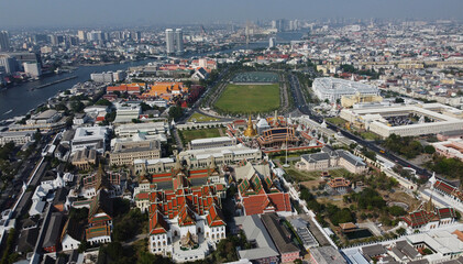 Obraz premium Aerial view of Grand Palace complex in Bangkok, Thailand. The Temple of the Emerald Buddha, right, Sanam Luang park and the Chao Phraya river are seen in the background.