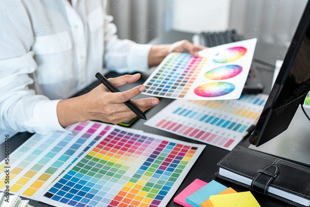 Poster Young creative graphic designer working on color selection and drawing on graphics tablet at workplace, Color swatch samples chart for selection coloring in inspiration to create new collection