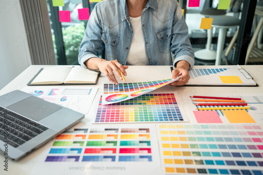 Poster Young creative graphic designer working on color selection and drawing on graphics tablet at workplace, Color swatch samples chart for selection coloring in inspiration to create new collection
