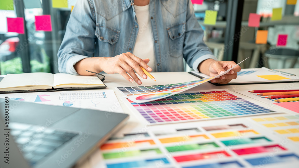 Poster Young creative graphic designer working on color selection and drawing on graphics tablet at workplace, Color swatch samples chart for selection coloring in inspiration to create new collection