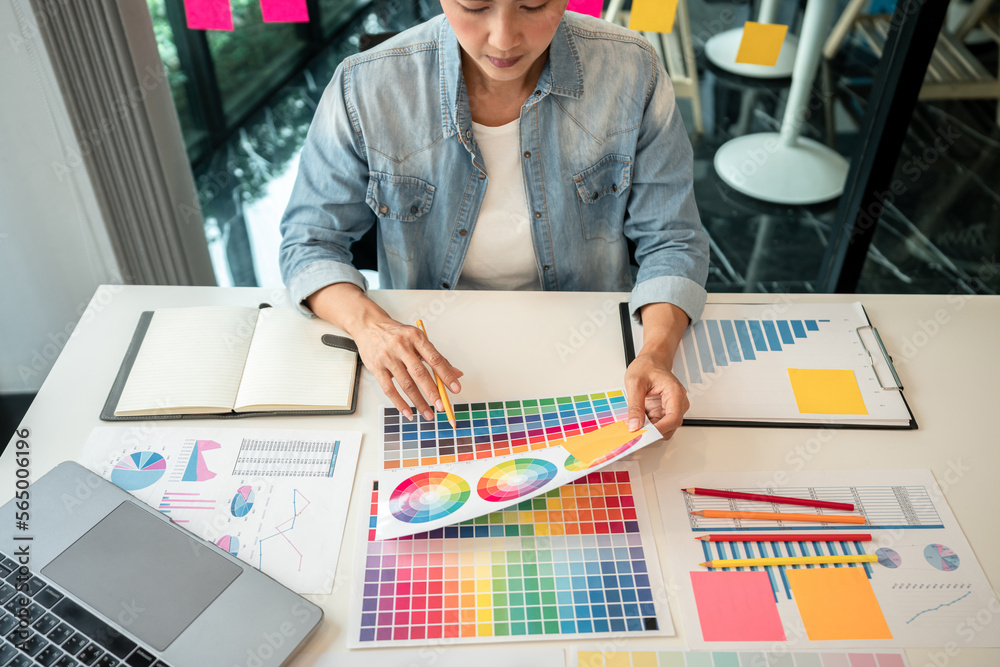 Poster Young creative graphic designer working on color selection and drawing on graphics tablet at workplace, Color swatch samples chart for selection coloring in inspiration to create new collection