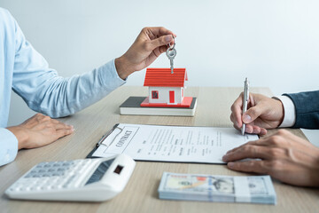 Real estate broker agent holding filing keys to the customer after signing rental lease contract of...