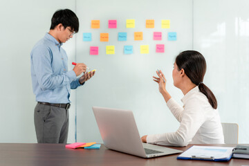Two business executive team holding and taking notes keyword on board wall to brainstorm about a...