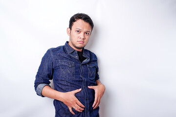 Fototapeta premium A portrait of insecure Asian fat man is holding the fat on his belly