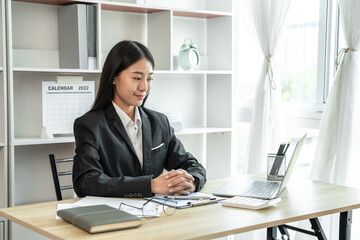 Freshman accounting worker smiles brightly on her first day of work, Private office and clean and tidy, Use a laptop to calculate and analyze financial data, Businesswoman in office concept