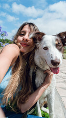 Vertical selfie portrait for social networks of young woman with her pet looking at the camera