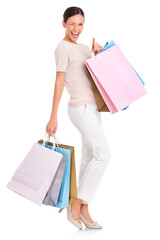 An attractive young woman carrying many shopping bags in both hands and pointing her finger towards...