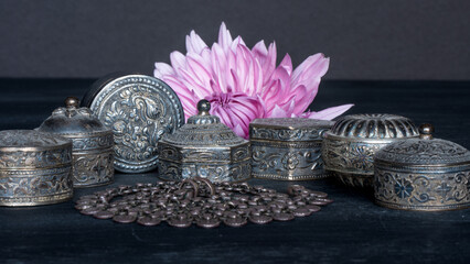 Closeup arrangement of traditional Omani silver pill boxes and a necklace.