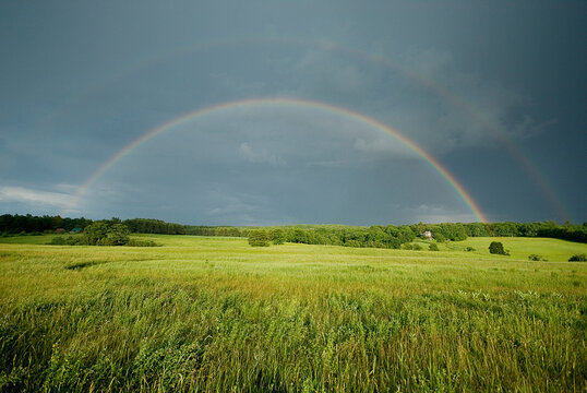 Double rainbow over hay field.