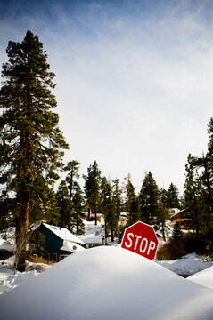 A stop sign is burried in a snow drift after a large winter storm.