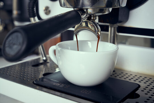 An espresso machine pours espresso into a coffee mug.
