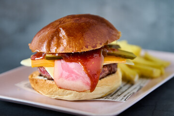 burger with cheddar cheese, bacon and pickle and fries