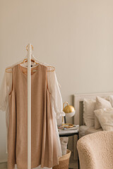 Female clothes on hanger in cozy bedroom. 