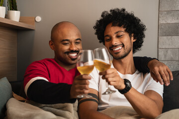 Couple in love makes a toast and smiles on the sofa in the living room at home