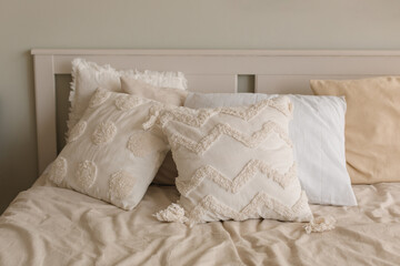 Pillows in stylish light covers on the bed. Decor in a cozy bedroom. 