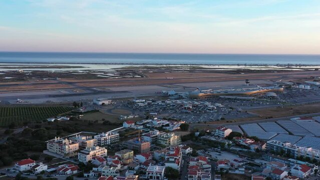Aerial view of Portuguese Faro Airport, airplanes and runways against the sea. On the Sunset.