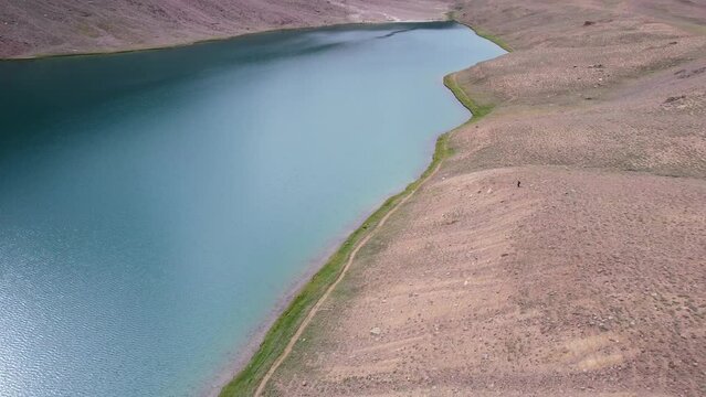 sun reflecting on glacier blue water at Chandra Taal Lake in India, aerial top down
