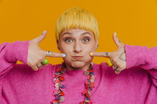 Young beautiful short-haired woman in necklace with puffed cheeks