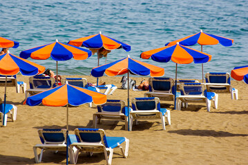 Beach scene of  tourists, sunbeds and parasols overlooking the blue Atlantic Ocean, Puerto del Carmen, Lanzarote, Canary Islands, Spain.