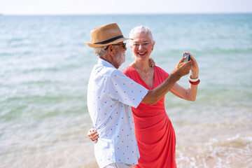 Couple of old mature people selfie together on the sand at the beach enjoying and living the moment