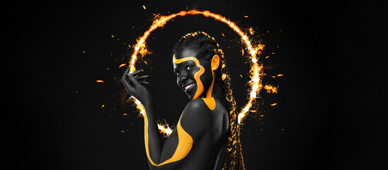 Woman on poster with face art. Yellow body paint. Girl with bodypaint. An amazing model with makeup. Black background.