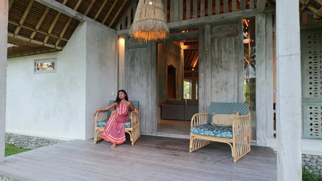 young asian model sitting in a bohemian patio chair at a luxury villa in Bali Indonesia