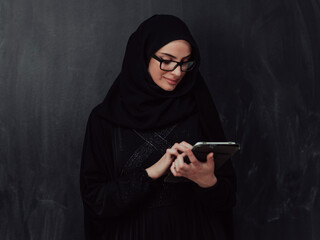 Young modern muslim business woman using smartphone wearing hijab clothes in front of black chalkboard