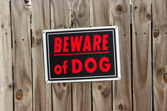 Beware of the dog sign on a wooden fence