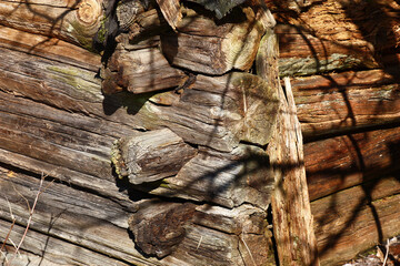 Small fragment of an old wooden shed. Two walls and a corner between them. Everything is well lit with the sun.