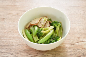 stir fried broccoli with green pea in oyster sauce topping slice grilled pork on bowl