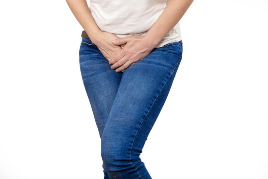 Cropped shot of a young woman in blue jeans with a need to go to the toilet on white background. Casual style.
