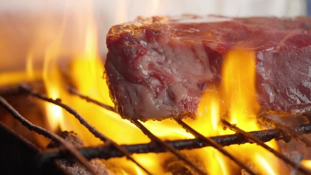 Close-up of grilled fillet steak between flames and embers of barbecue charcoal