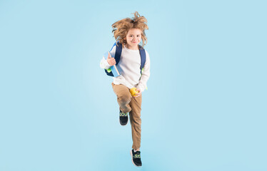 Obraz premium Kid jump and enjoy school. Full length body of little school kid jumping having fun isolated blue background. Crazy school boy jump.