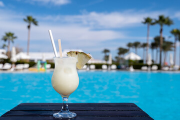 Pinacolada summer cocktail on the wooden table near the swimming pool, all inclusive resort