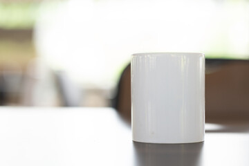 A tea mug standing up on a table with bright blurred out background