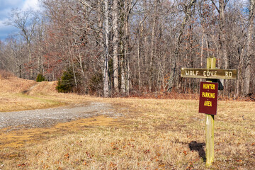 Wooden road sign on an unpaved mountain trail in a winter forest and a deer hunters parking area. Wolf Cove Road in Tennessee on Bear Creek Wildlife Management Area